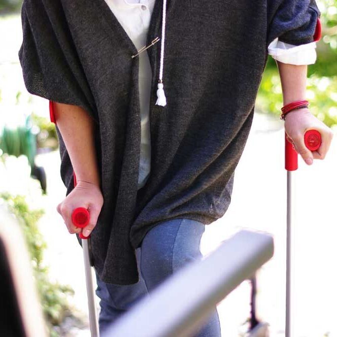 Eine Person läuft an zwei Krücken mit roten Griffen