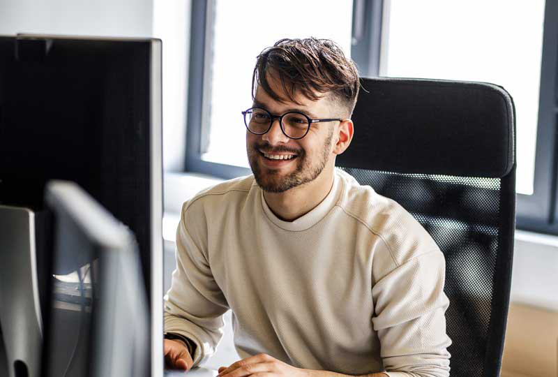 Junger Mann sitzt am Computer für Stellenanzeige AI Product Builder / Vibe Coder (m/w/d)
